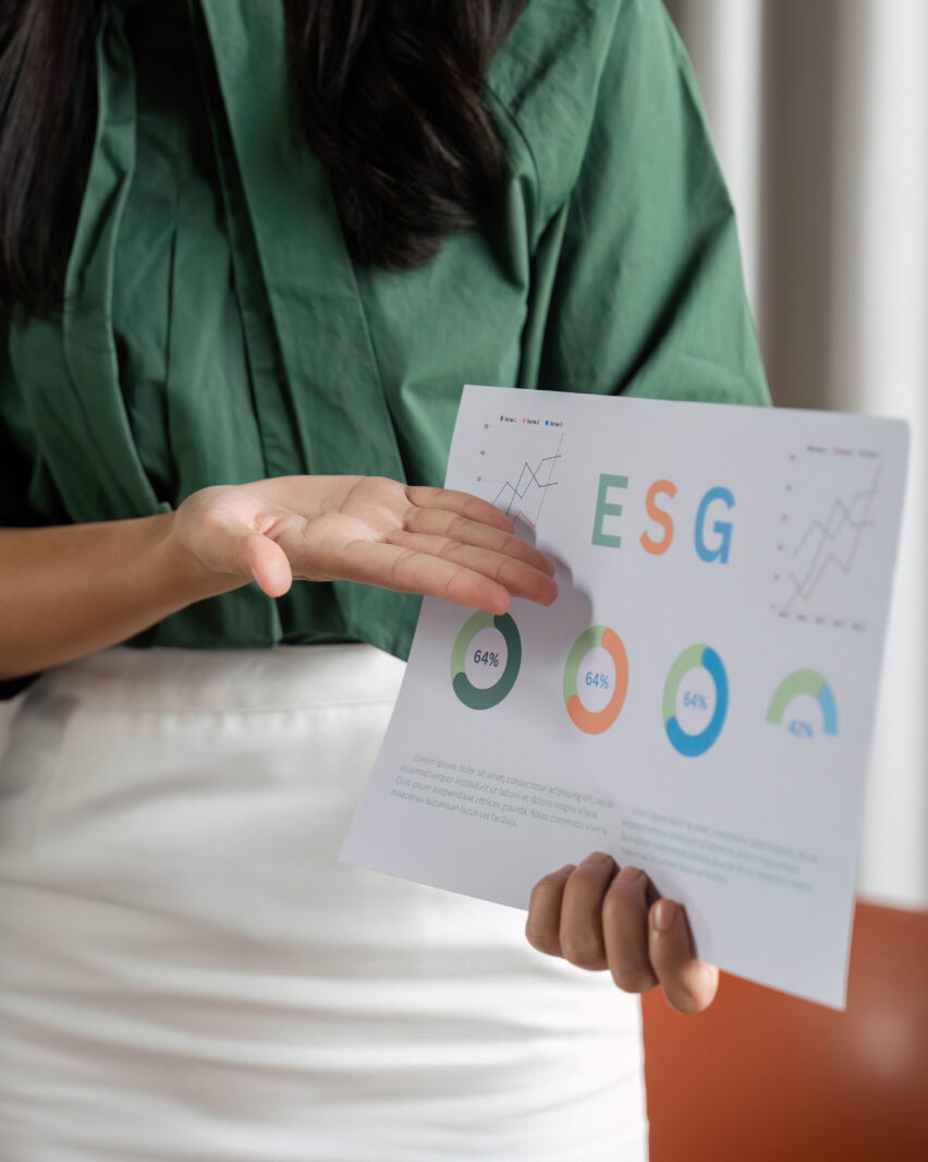 A professional woman highlights ESG metrics with charts, promoting sustainable practices during a corporate discussion.